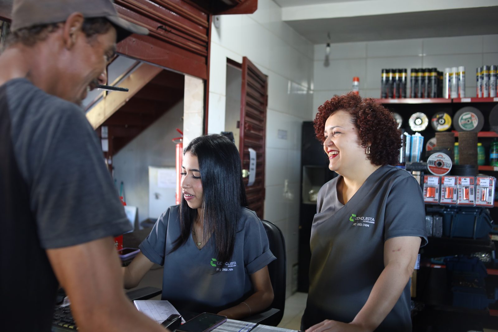 Equipe da Conquista Reciclagem atendendo um cliente no balcão
